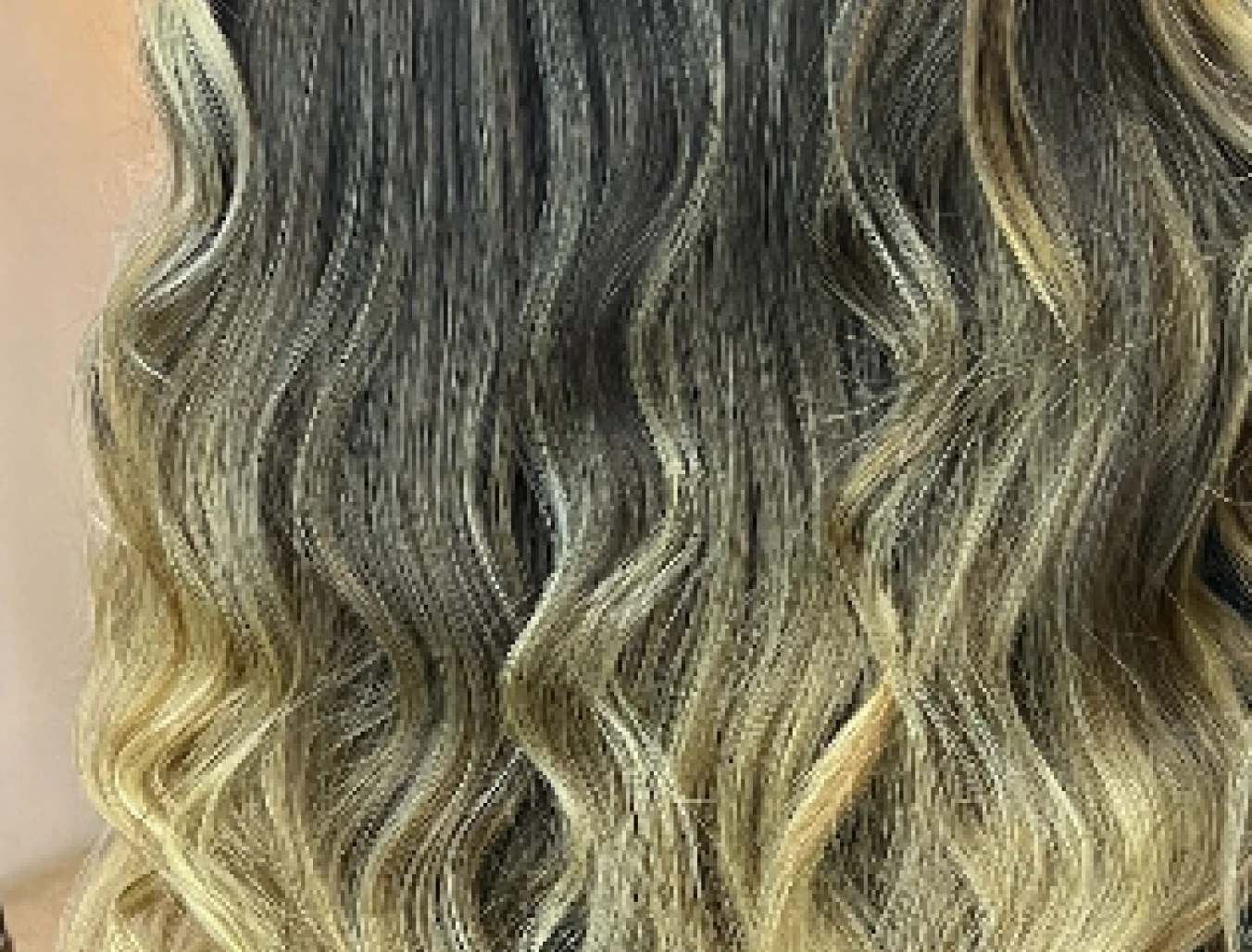 Cabello largo con ondas rubias y raíces oscuras mostrando un estilo degradado