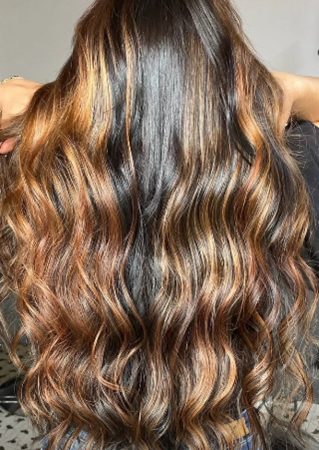 Cabello oscuro con reflejos cobrizos y ondas naturales visto desde atrás