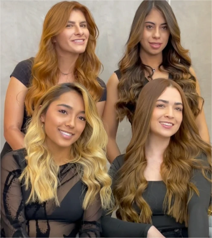 Cuatro mujeres con diferentes estilos y tonos de cabello luciendo peinados ondulados en un salón de belleza con fondo neutro