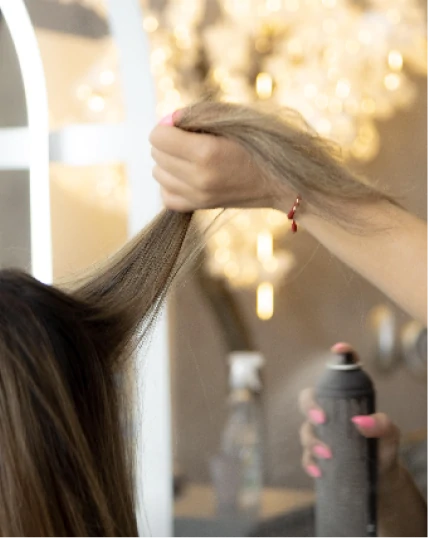 Mechón de cabello sostenido mientras aplican spray de peinado