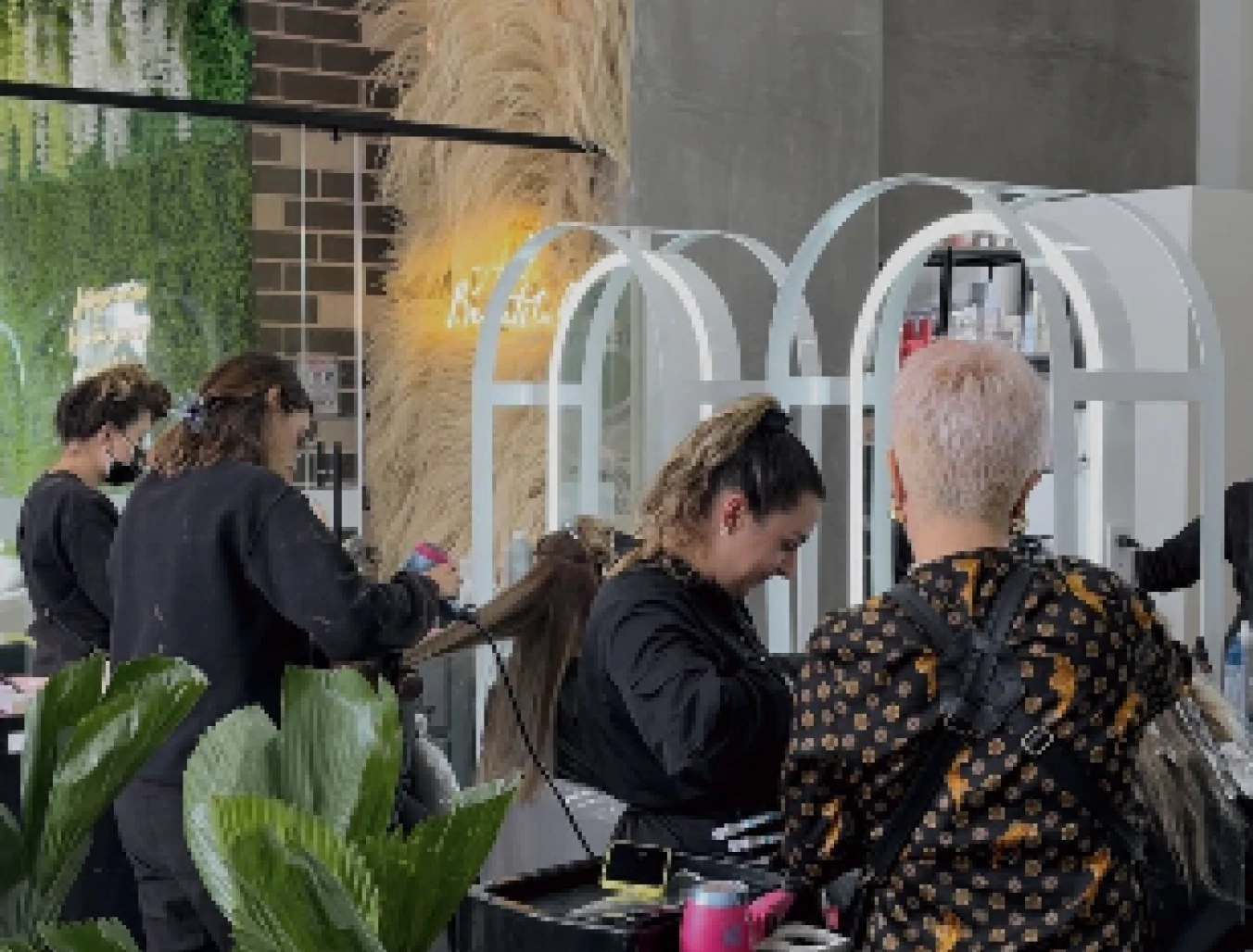 Salón de belleza moderno con estilistas trabajando y decoración natural con plantas